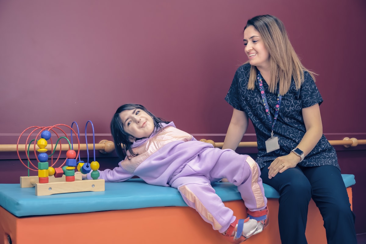 A clinician working one-on-one with a child using a wooden sensory learning toy on a therapy mat