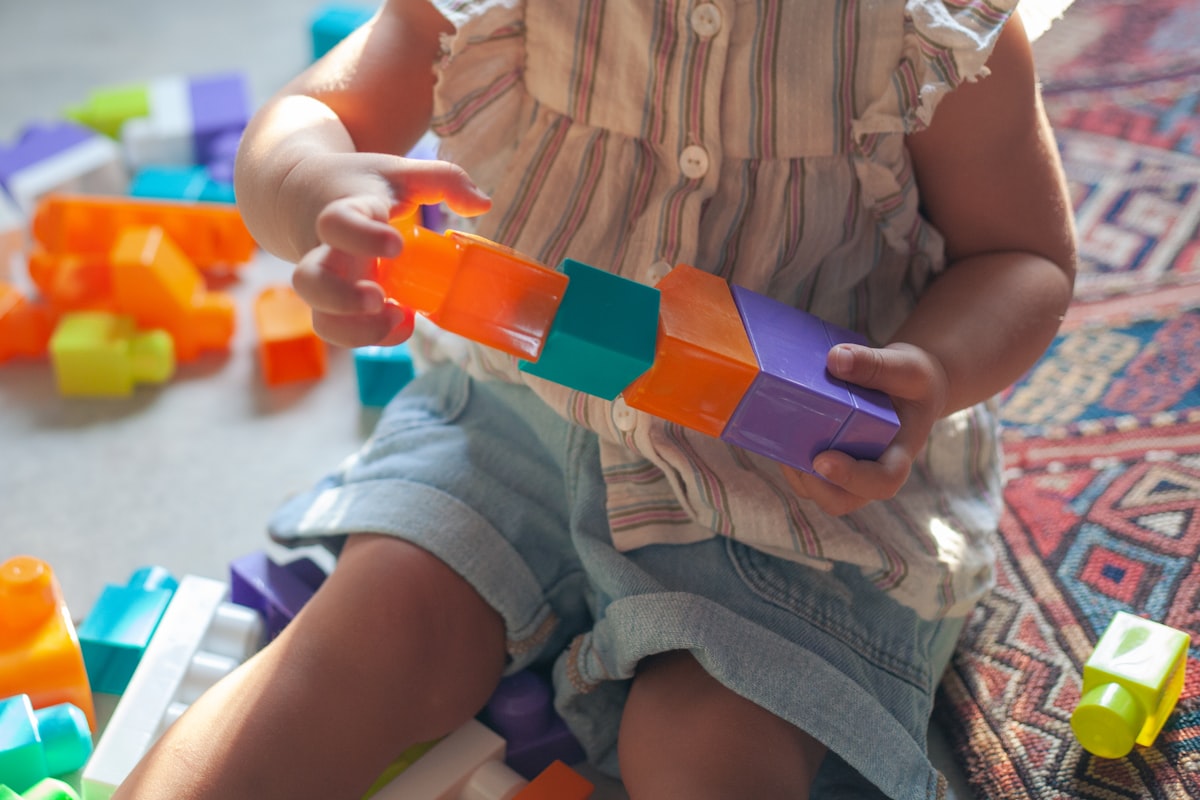 A child engaged in hands-on skill-building play with colorful blocks